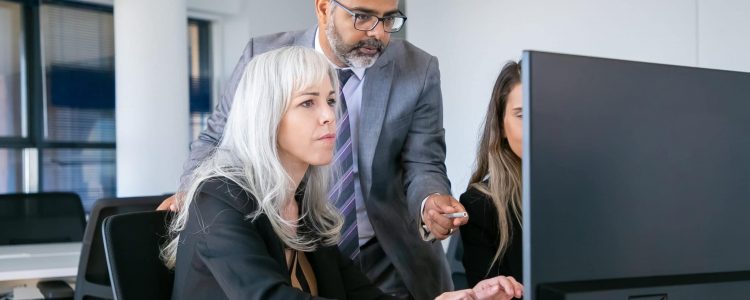 Boss looking and pointing at monitor, commenting project while manager typing and working on presentation. Medium shot. Business communication concept