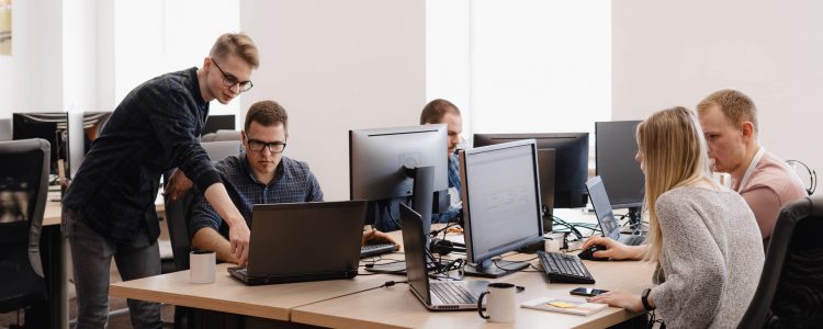 Full concentration at work. Group of young business people working and communicating while sitting at the office desk together with colleagues sitting in the background