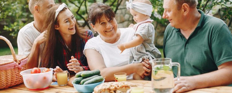 Family sitting in the yard. Mother and little daughter near the house. Big family on a picnic