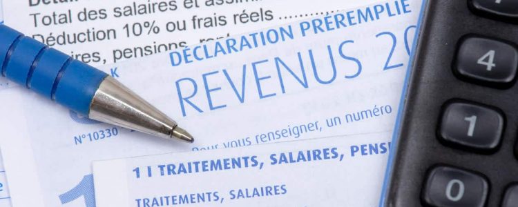 French pre-filled income tax return with the page about income from salaries, treatments, pensions and annuities, along with a pen and a calculator